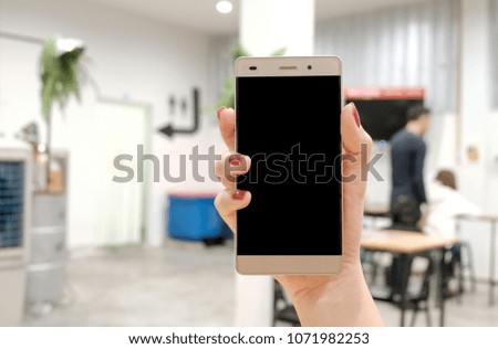 Woman hand holding the phone on Blurry Restaurant background