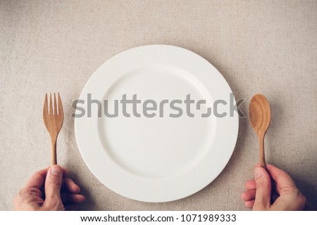 white plate with spoon and fork, Intermittent fasting concept, ketogenic diet, weight loss, food crisis, inflation concept Royalty-Free Stock Photo #1071989333
