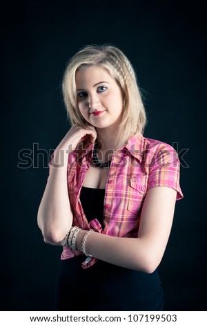Portrait of blonde teenager girl on black background.