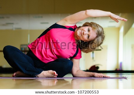 Mature Woman Does Yoga Side Bend Royalty-Free Stock Photo #107200553