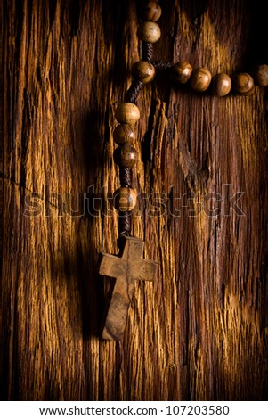 Wooden rosary beads hanging on the old wooden background