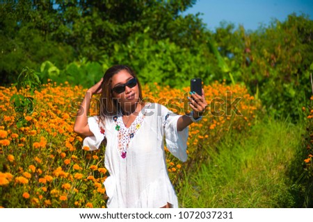 happy and beautiful young Asian tourist woman taking selfie pic in gorgeous orange marigold flowers field natural landscape in travel destination and holidays Summer trip tropical excursion