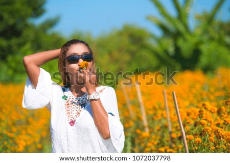 happy and beautiful young Asian woman relaxing enjoying the fresh beauty of gorgeous orange marigold flowers field natural landscape in travel destination and holidays Summer trip tourist excursion
