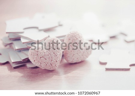 Two ceramic white heart over pile of jigsaws on wooden table, Conceptual image show most important part of human life is love