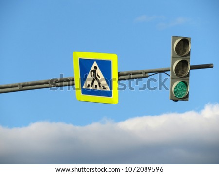 Pedestrian crossing sign and green traffic light on blue cloudy sky background. Free way or Good way concept
