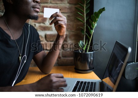 Close up of afro american man hands with white blank card for copy space in front of laptop and table background