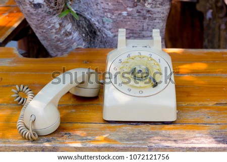An old classical vintage telephone color cream on the wooden table, the handset is not put on the phone