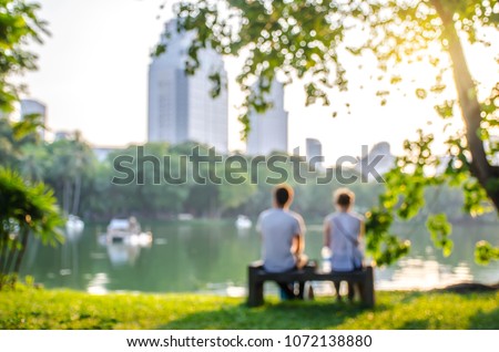 blurred and soft focus, a girl and a man sitting on a Park bench by the lake. The blurred and bokeh background
