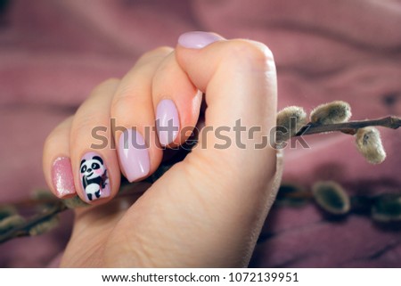 Nails with a pastel color and a picture of a cute panda, in whose hands are the spring branches. In the hand, on the fingers of which the manicure is a real branch with fluffy buds.