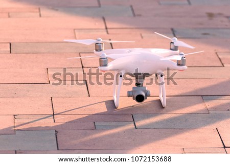 The white quadrocopter takes off over the sidewalk.