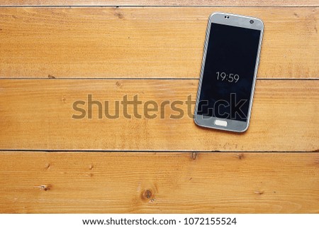 Top view with copy space. smartphone with digital clock's on wooden desk, ready for adding text or mockup.