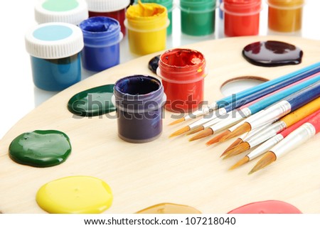 wooden art palette with  paint and brushes isolated on white
