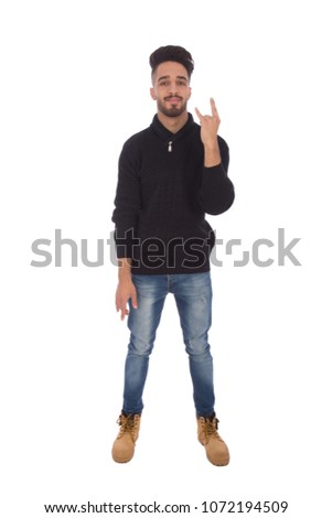 Full-length shot of a handsome young man wearing winter outfit and doing rock and roll sign, isolated on white background