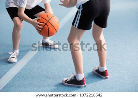 Cropped photo of pupils playing basketball in the gym Royalty-Free Stock Photo #1072218542