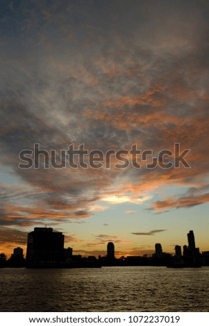 Sunset sky by the river, showing the shadow of the Busytown town .
The sun coloring sky shades of many colors -orange ,pink yellow ,grey. The picture is in vertical angle.