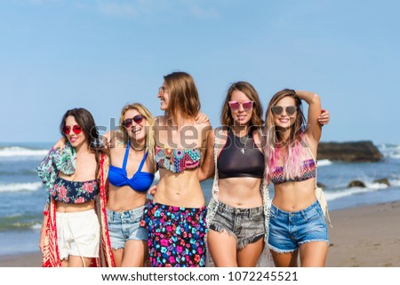 group of happy young women in bikini spending time together on beach