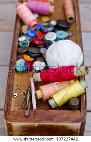 Colorful threads and old scissors on the old wooden table/Old sewing accessories