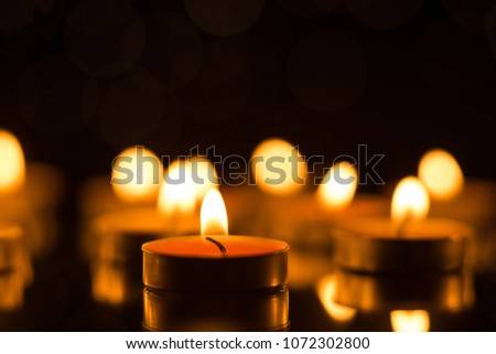 Candles in the dark with reflection and shallow depth of field, with lights in the background