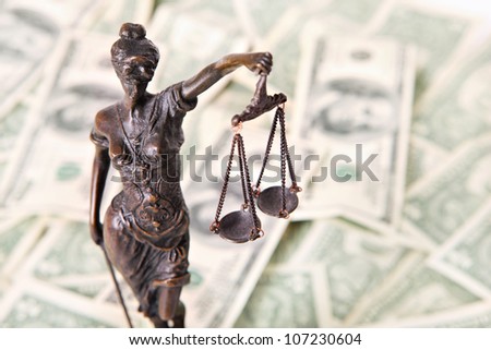 A picture of a Themis statue standing over dollar notes background
