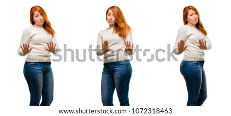Young Beautiful redhead woman annoyed with bad attitude making stop sign with hand, saying no, expressing security, defense or restriction, maybe pushing