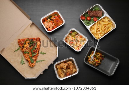 Different containers with delicious food on wooden table. Delivery service Royalty-Free Stock Photo #1072334861