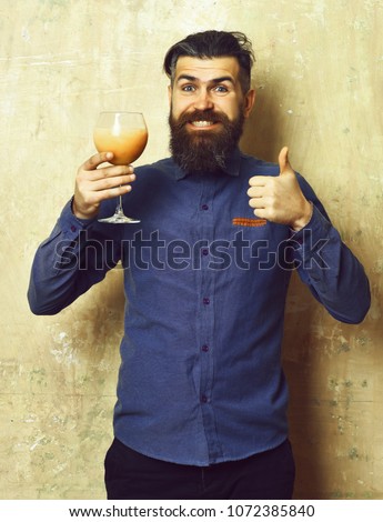 Bearded man, long beard. Brutal caucasian smiling happy hipster with moustache in blue denim shirt holding alcoholic fresh cocktail on texture background