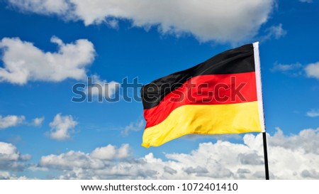 German flag waving against blue sky.