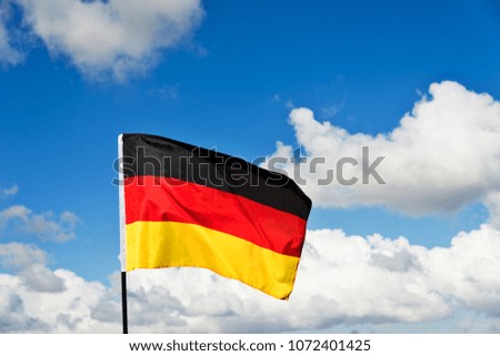German flag waving against blue sky.