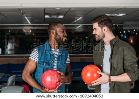 happy young men with balls at bowling club