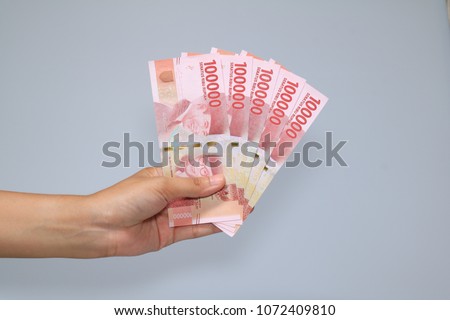 woman hand showing rupiah Indonesian money Royalty-Free Stock Photo #1072409810