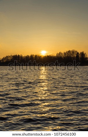 Beautiful nature and landscape photo of colorful sunset at spring evening in Sweden Scandinavia Europe. Nice outdoors image with lake, trees and sky. Calm, peaceful background picture.