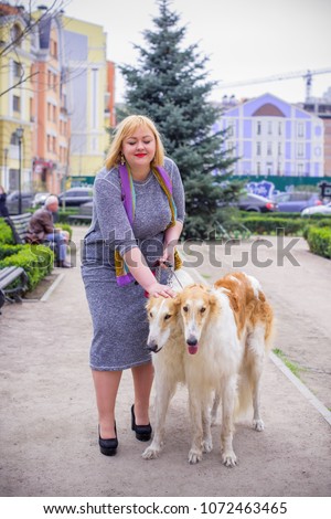 Plus size woman on a walk with dog of Russian hound greyhound breed. Pets and human, friends of people