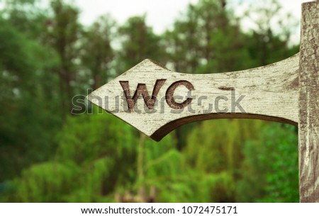 A vertical view of vintage simple design handmade wooden sign of toilet give direction to WC
