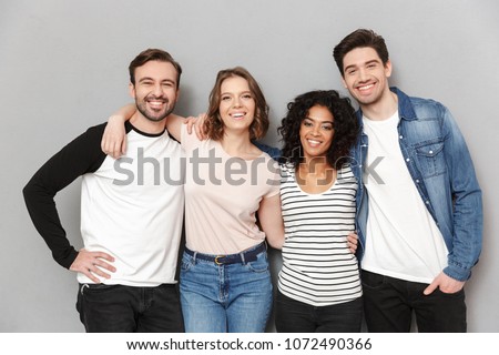 Image of happy group of friends standing isolated over grey wall background looking camera.