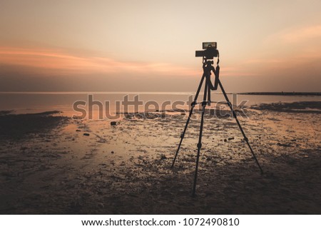 Dslr digital professional camera stand on tripod photographing sea, twilight sky and cloud landscape. nature background.image,picture on screen. dslr camera shoting nature landscape.camera on a tripod