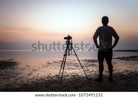 The Photographer takes a good shot on the Huahin beach, Thailand. photographer shoots video of the sunrise in the morning at low tide