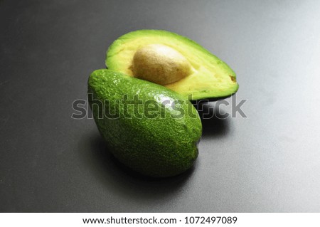 The green avocado halves lies on a dark background