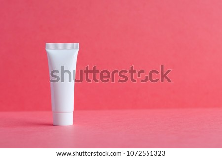 White cosmetic tube pack on pink background. Blank plastic container, mock up simplified packaging design. shallow depth of field, copy space photography.