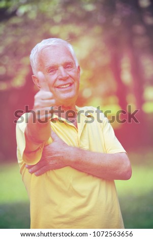 happy healthy and fit elderly man portrait  in green background park
