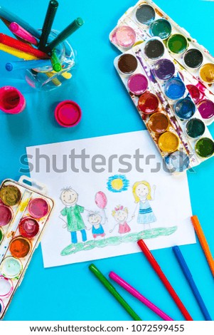 Children drawing pencil happy family mom, dad, son, daughter sunny day on the lawn and paint accessories, brush, felters gouache, watercolor on a blue background flat lay top view from above