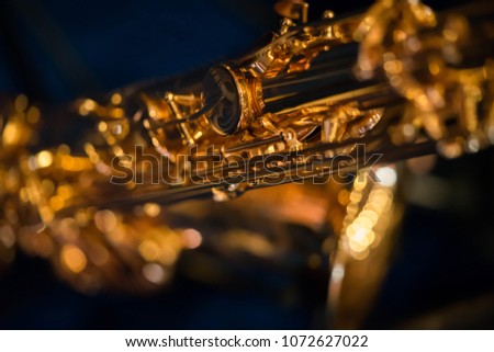 Close up picture the part of valve gold saxophone in blue background.