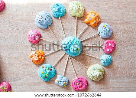 candy shop icon. meringue on stick as colorful sweets with sprinkles. meringue in roung shape on wooden background. fair and circus mood. bubble gum on wooden stick. mock up vintage dessert.