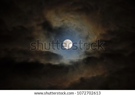 Wolf moon. The moon looks through an opening in the clouds.