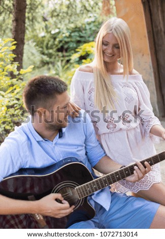 male and female sitting and enjoying playing guitar together