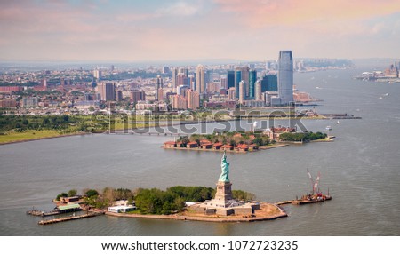 Sunny evening in New York. Helicopter view of Statue of Liberty and Jersey City.