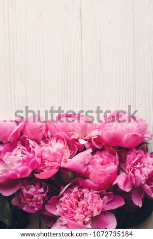 lovely pink peonies bouquet on rustic white wooden background top view, space for text. floral greeting card mock-up, flat lay. happy mothers day concept. spring image. pink flowers