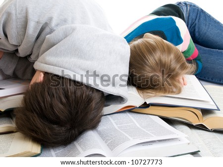 Two tired students sleep on books