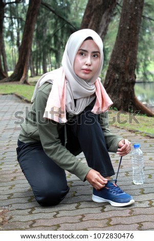 beautiful women are fixing their sports shoe strap during workout in the park