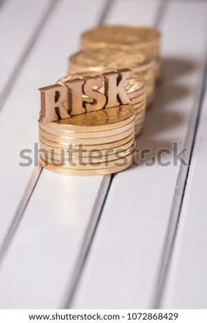 Wooden RISK word with golden coin on white table top