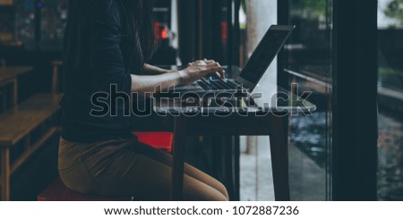 Low key picture style of young Asian girl working at a coffee shop with a laptop.female freelancer connecting to internet via computer. Casual Thinking Browsing Concept